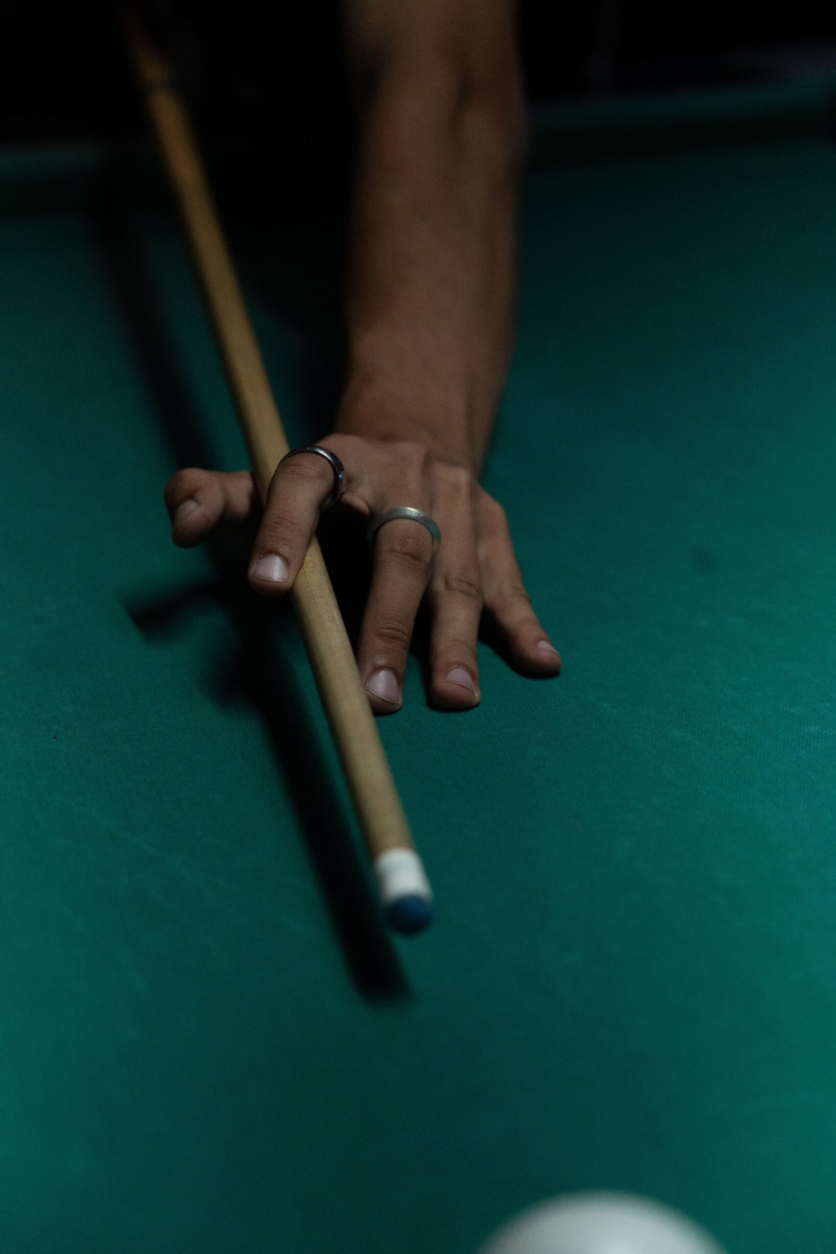 Player aiming a pool cue toward a billiard ball on a green table